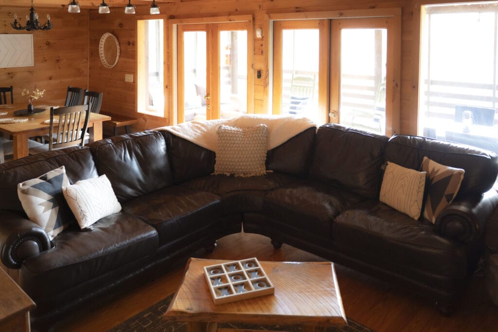 Living room of the Lincoln Logs Cabin with a large L shaped sofa, as well as the dining room